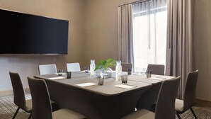 A conference room with a large table, chairs, a flat-screen TV, and a window with curtains. - Kimpton Armory Hotel Bozeman by IHG (Bozeman)