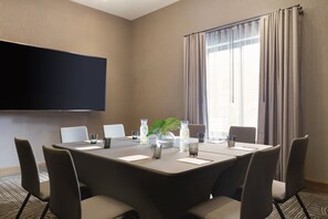 A conference room with a large table, chairs, a flat-screen TV, and a window with curtains. - Kimpton Armory Hotel Bozeman by IHG (Bozeman)