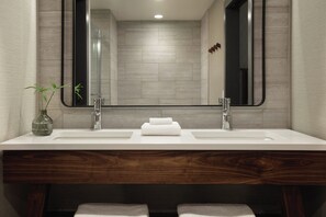 Un baño moderno con tocador de madera, dos lavamanos y un espejo grande.