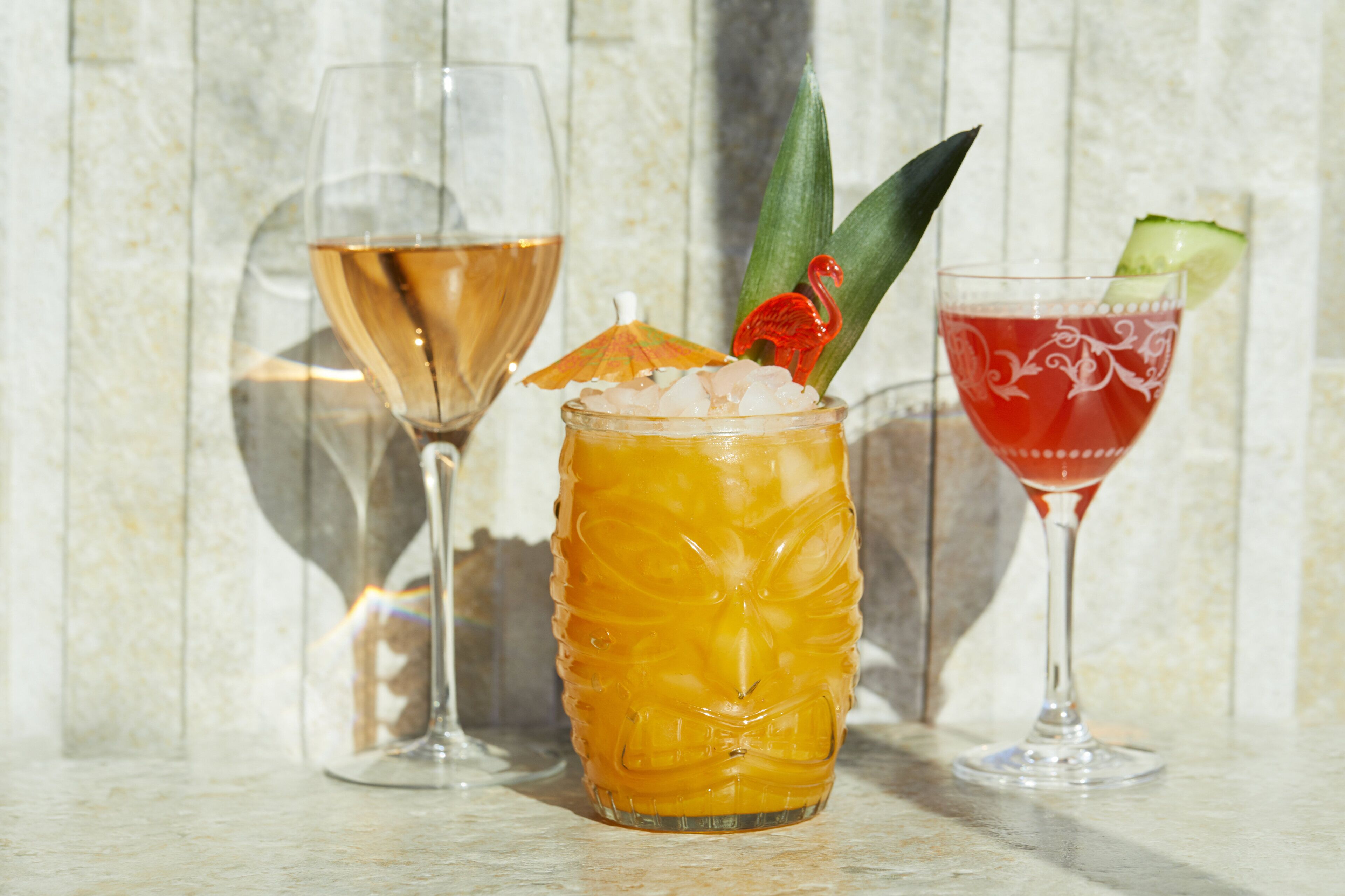 Three glasses of different beverages on a marble surface.