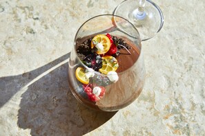 Un vaso transparente con un postre, posiblemente de chocolate, decorado con frutas y una cucharada de crema, sobre una superficie texturizada.