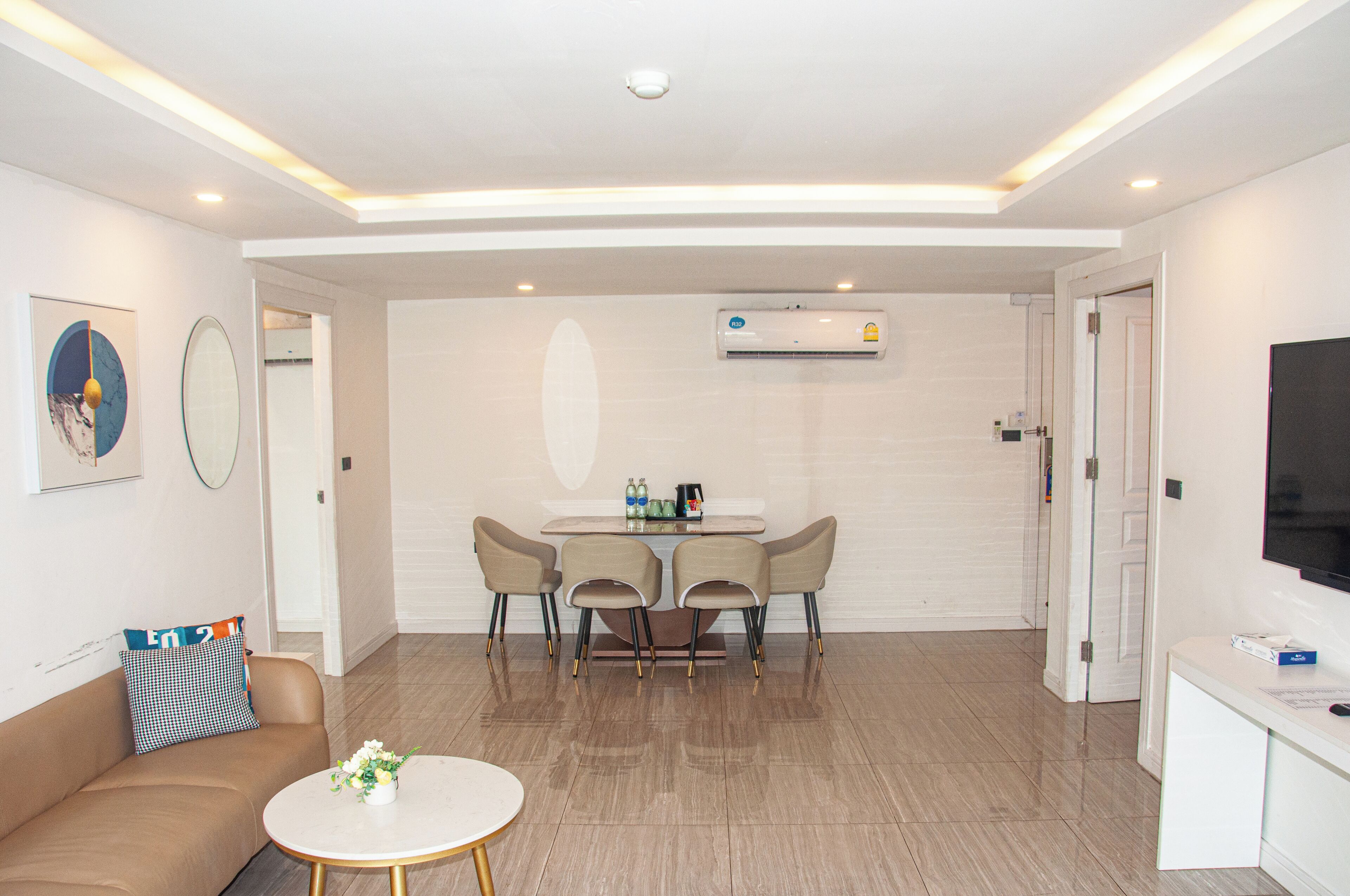 A modern living room with a brown sofa, a round coffee table, and a dining area with a table and four chairs.
