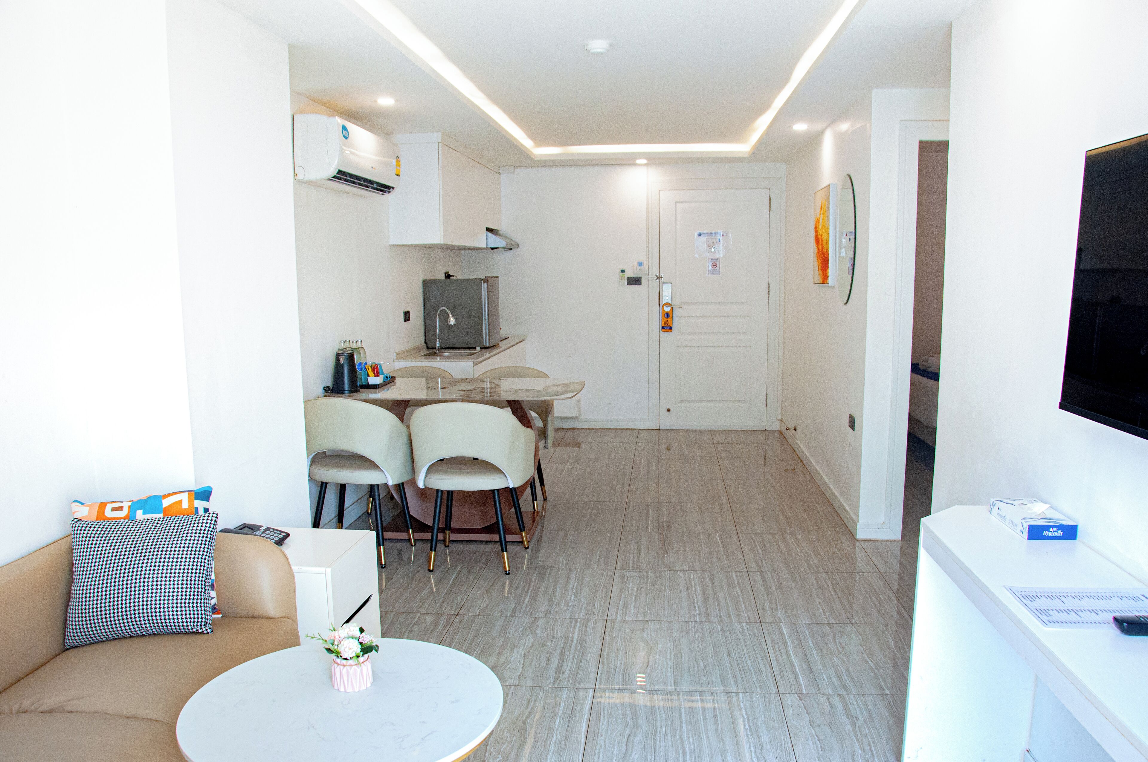A compact living space with a kitchenette, a dining area with chairs, a sofa, and a TV.