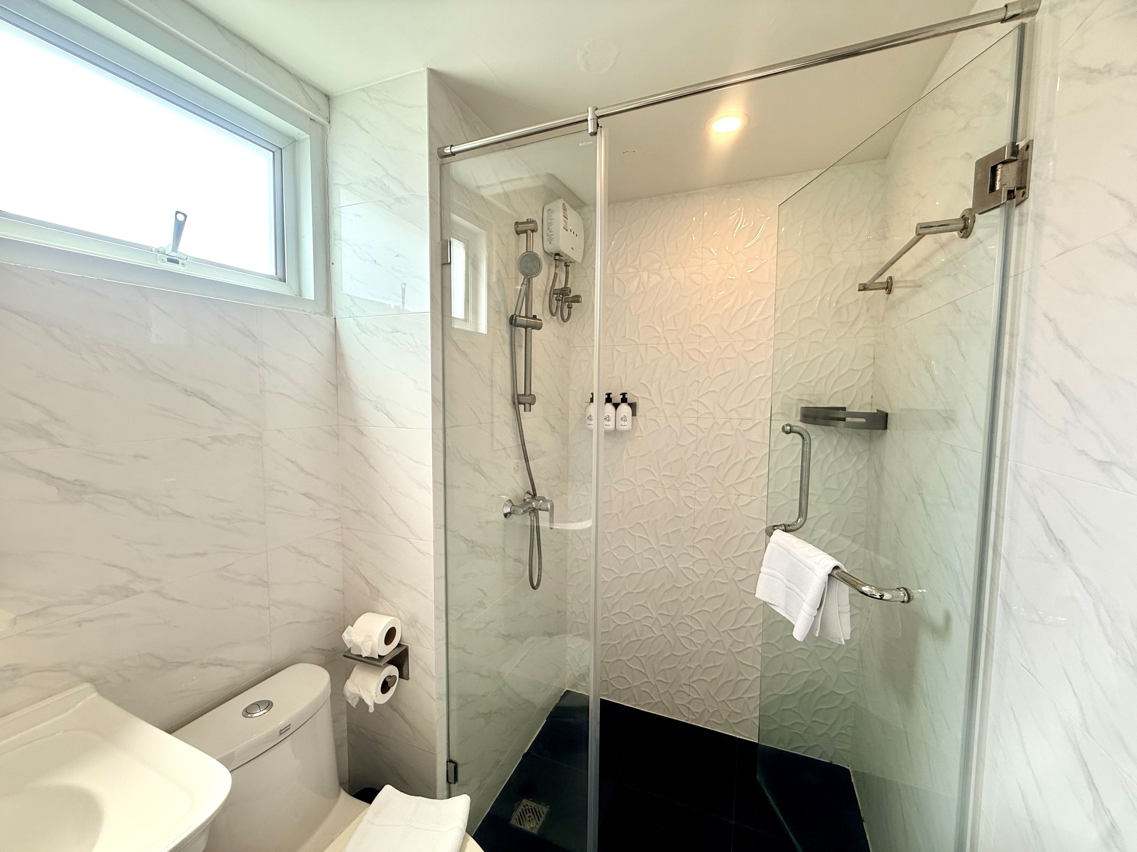 A modern bathroom with a glass-enclosed shower, a toilet, and a sink.