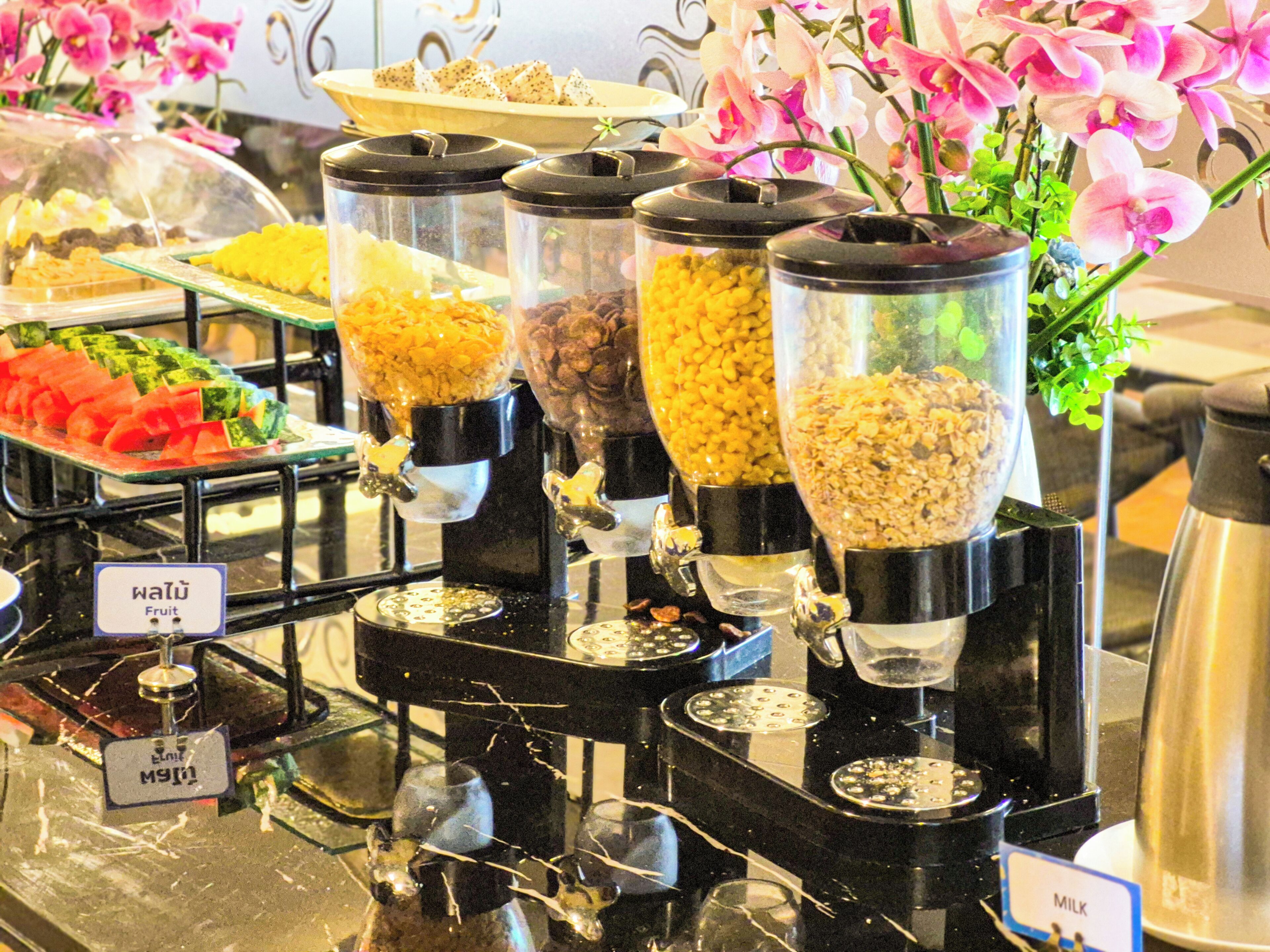 Un buffet avec des distributeurs clairement étiquetés pour les fruits, les céréales et le lait.