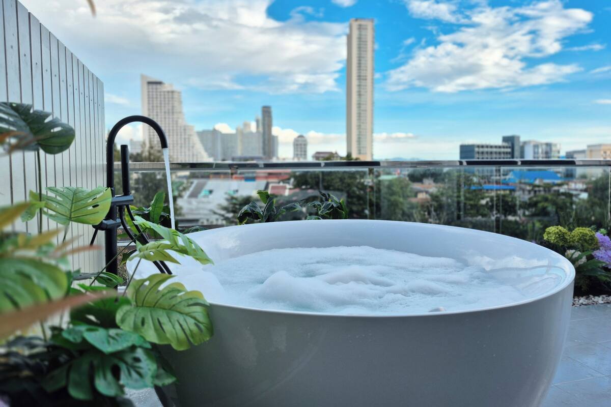 A hot tub on a balcony with a city view.