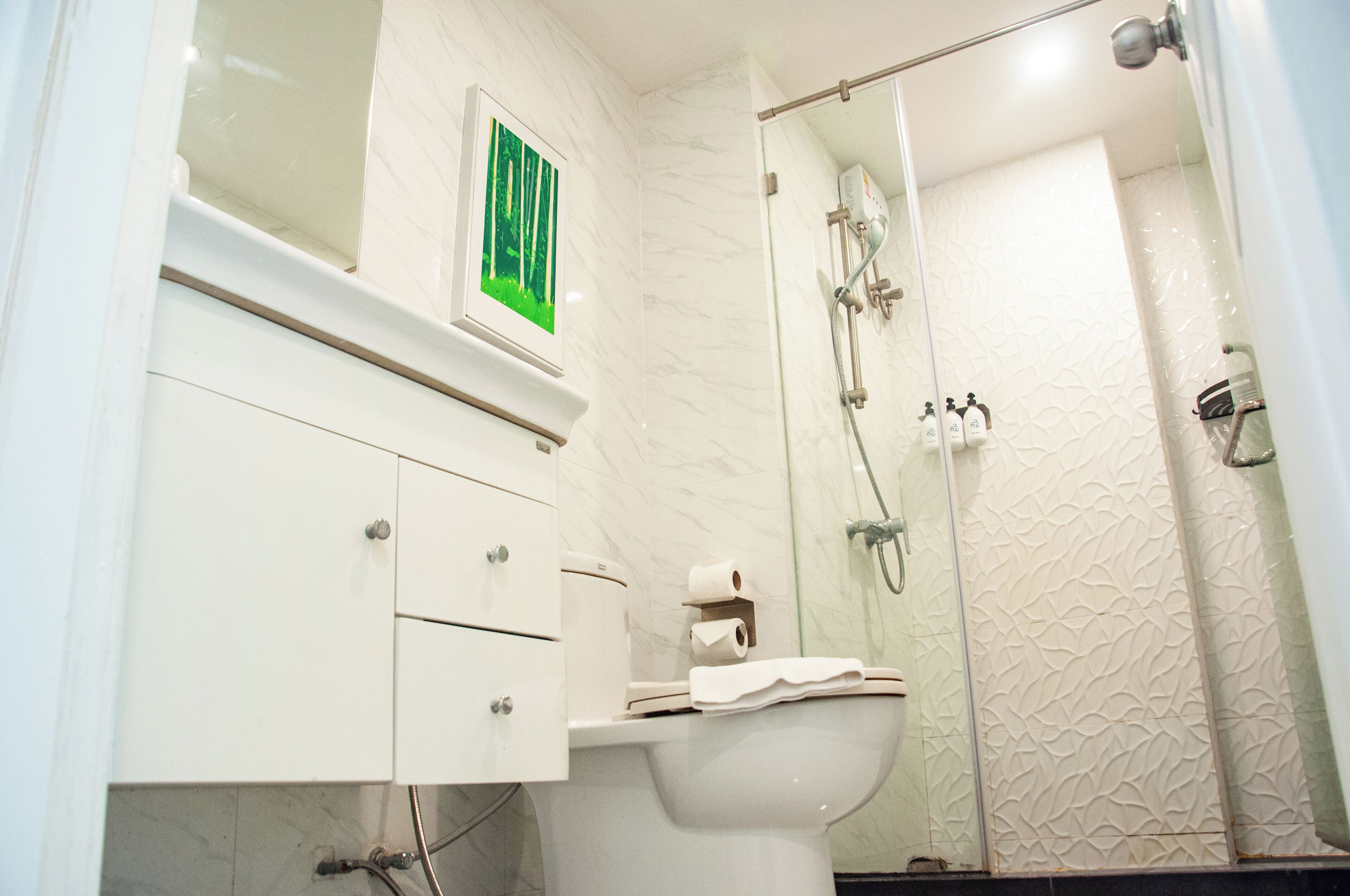 A bathroom with a toilet, a sink, a mirror, and a shower.