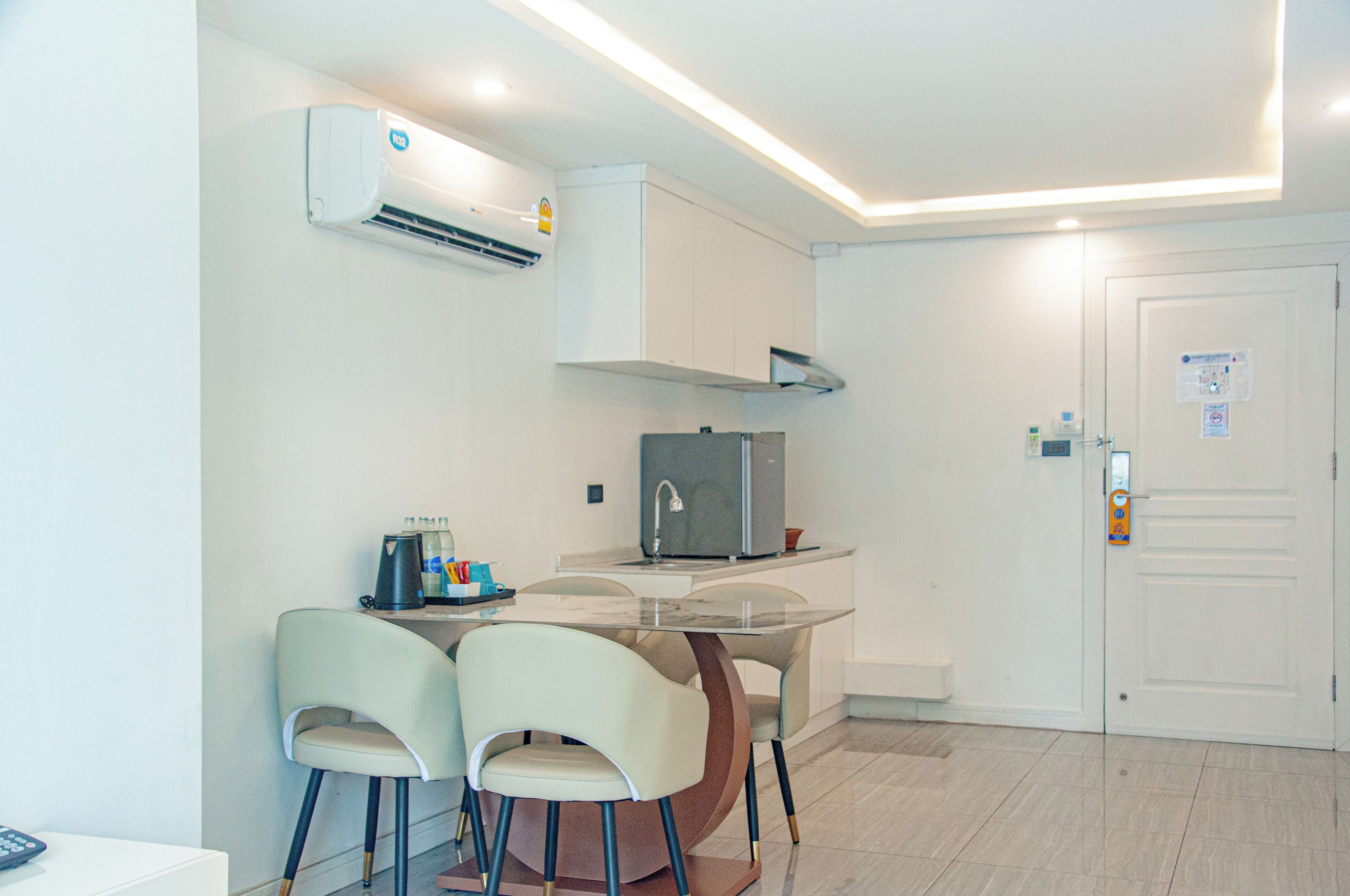 A compact kitchen with a refrigerator, a coffee maker, and two chairs.
