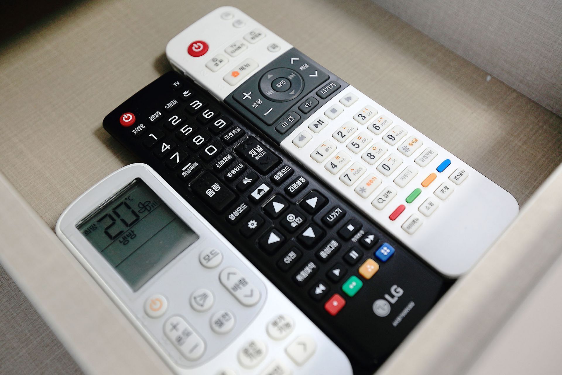 Três controles remotos de diferentes marcas e modelos.