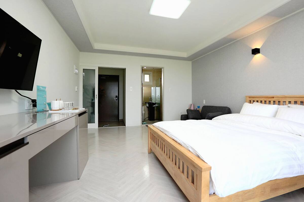 Ein modernes Hotelzimmer mit einem hölzernen Bett, einem Schreibtisch und einem Flachbildfernseher.