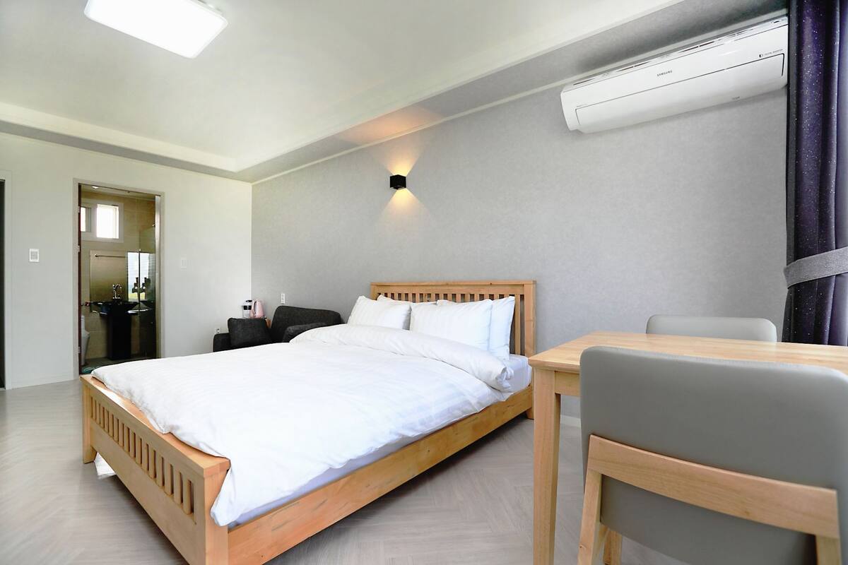 Ein modernes Hotelzimmer mit einem hölzernen Bett, einem Schreibtisch und einer Klimaanlage.