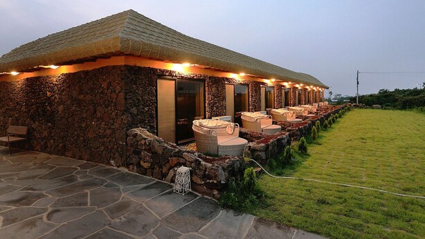 A stone building with a thatched roof, outdoor seating, and a stone pathway leading to the entrance.