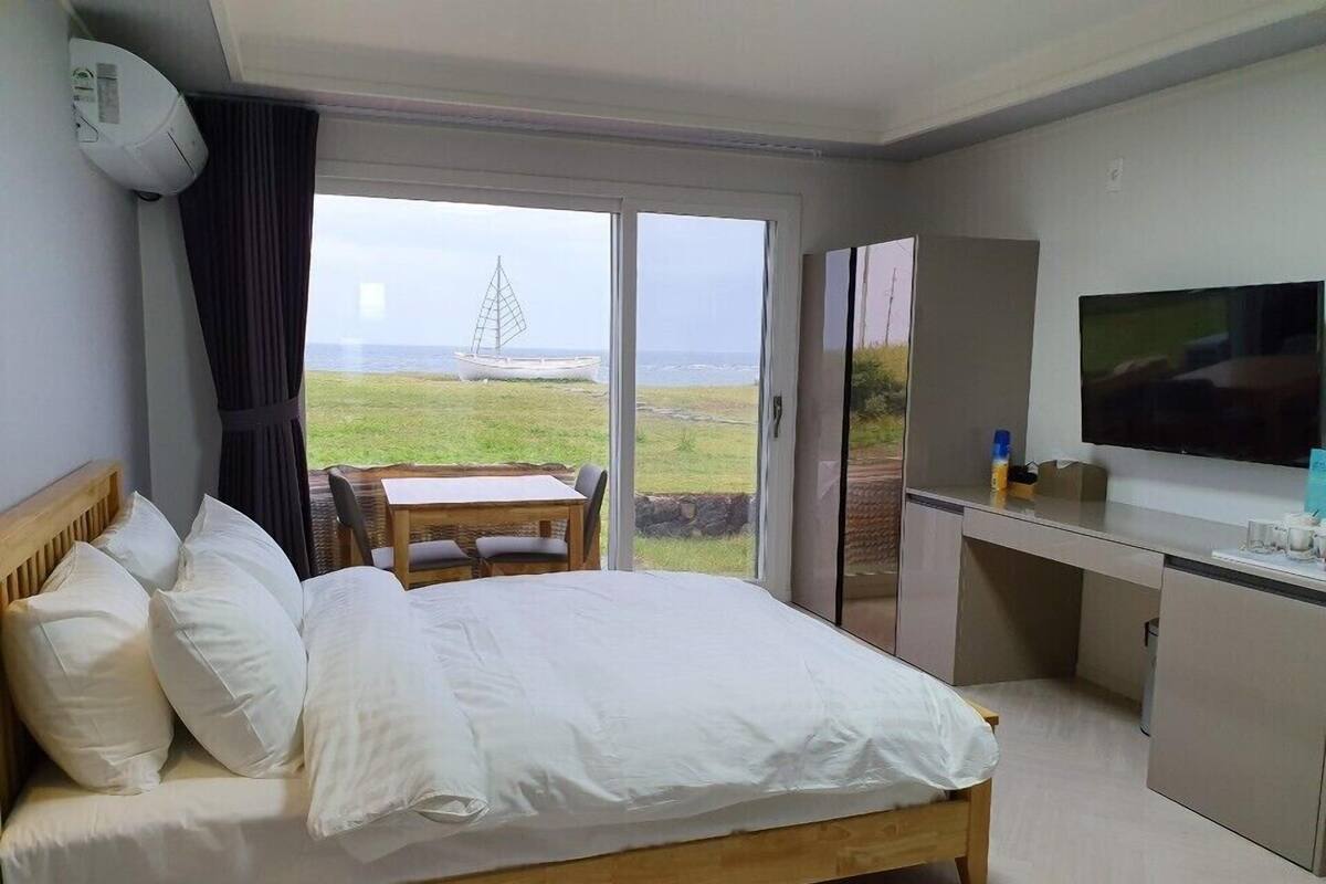 Ein Hotelzimmer mit Bett, Schreibtisch, Fernseher und Meerblick.