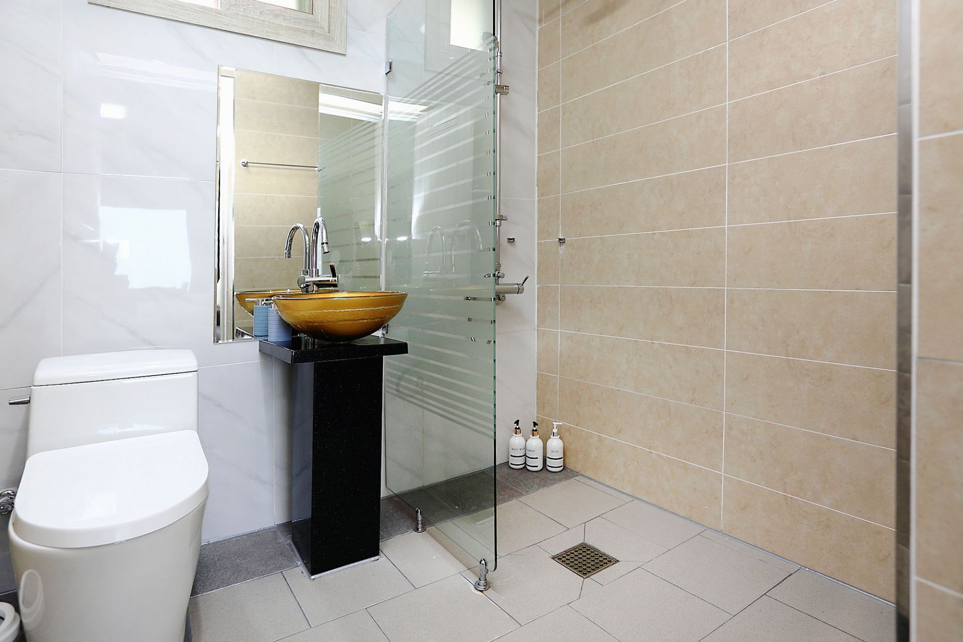 A modern bathroom with a glass-enclosed shower, a white toilet, and a vessel sink.