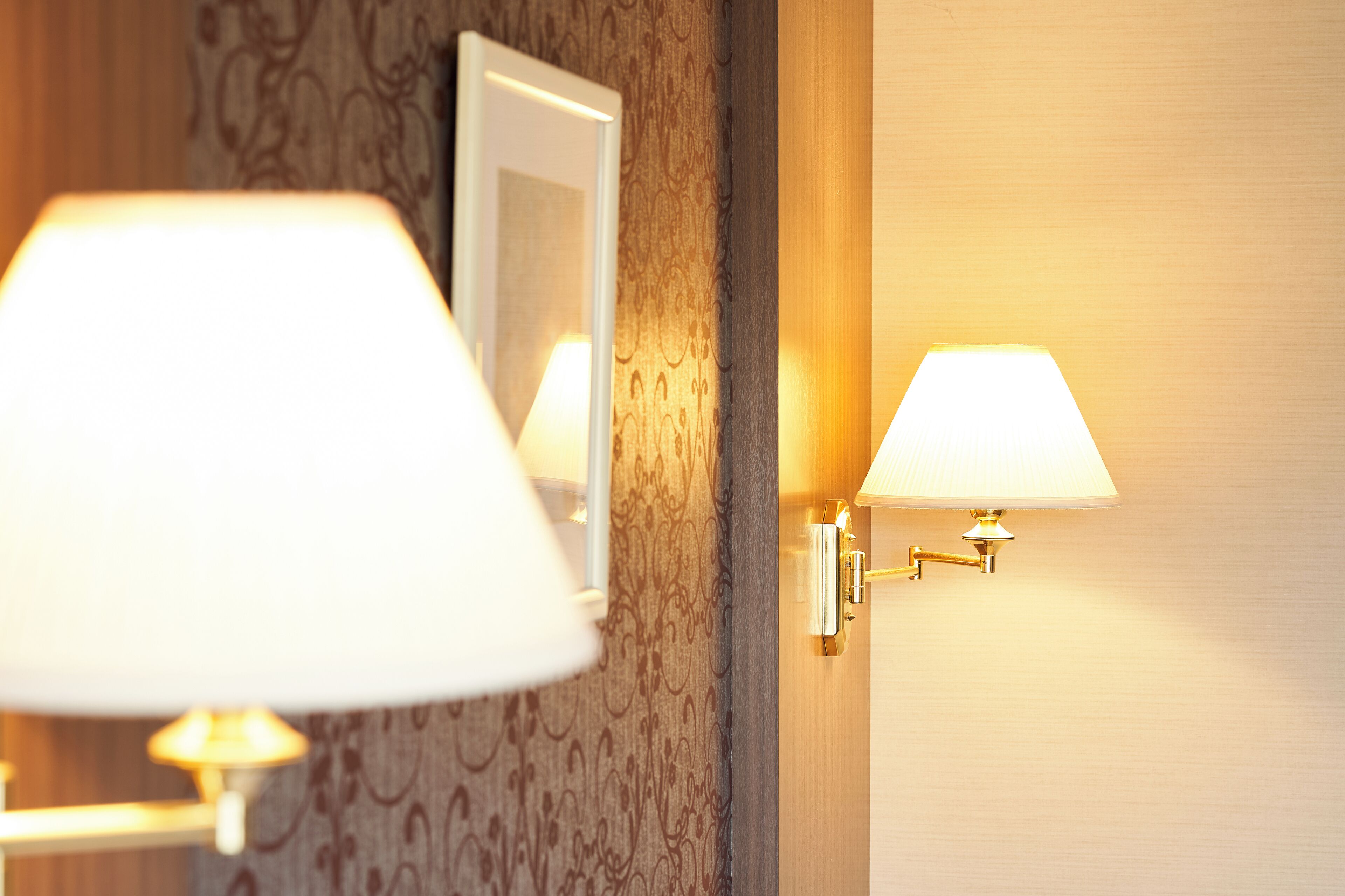 Eine Wandleuchte und eine Stehlampe in einem Raum mit Muster-Tapete.