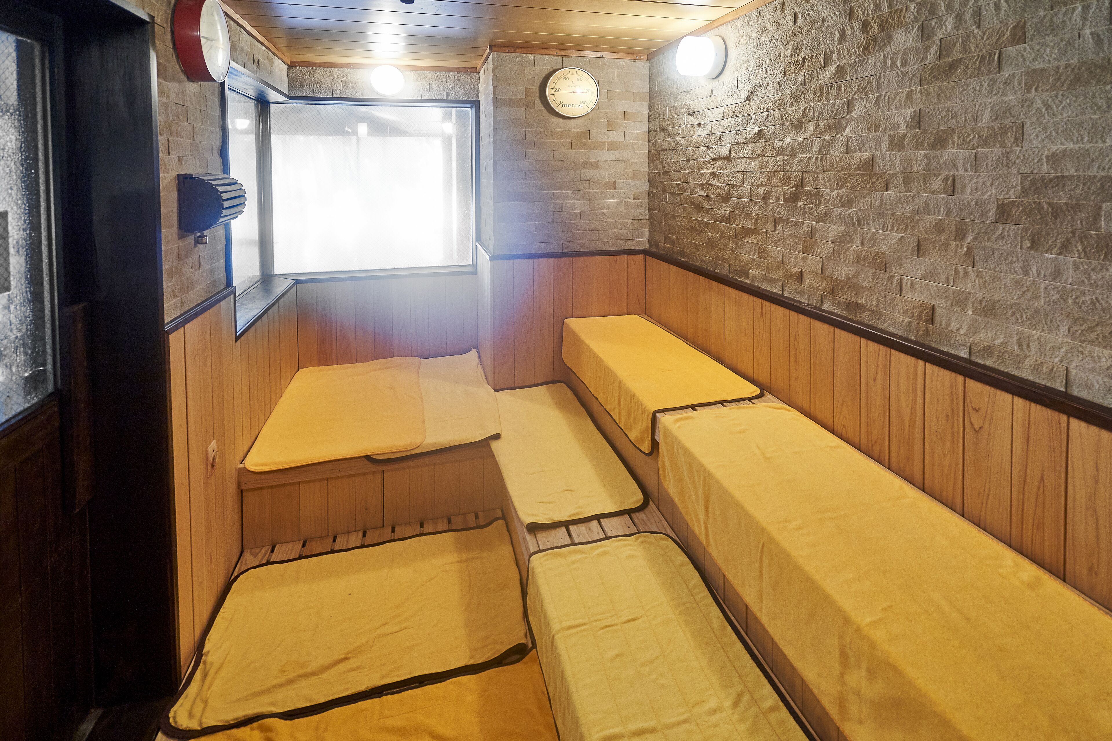 A sauna room with wooden benches and a brick wall.