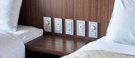A hotel room with a wooden headboard, a bedside table, and four electrical outlets.
