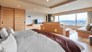 A modern hotel room with a large bed, a desk, a sofa, and a television.