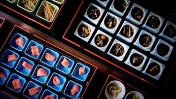 A variety of dishes arranged in square and rectangular containers, likely part of a buffet or food service.
