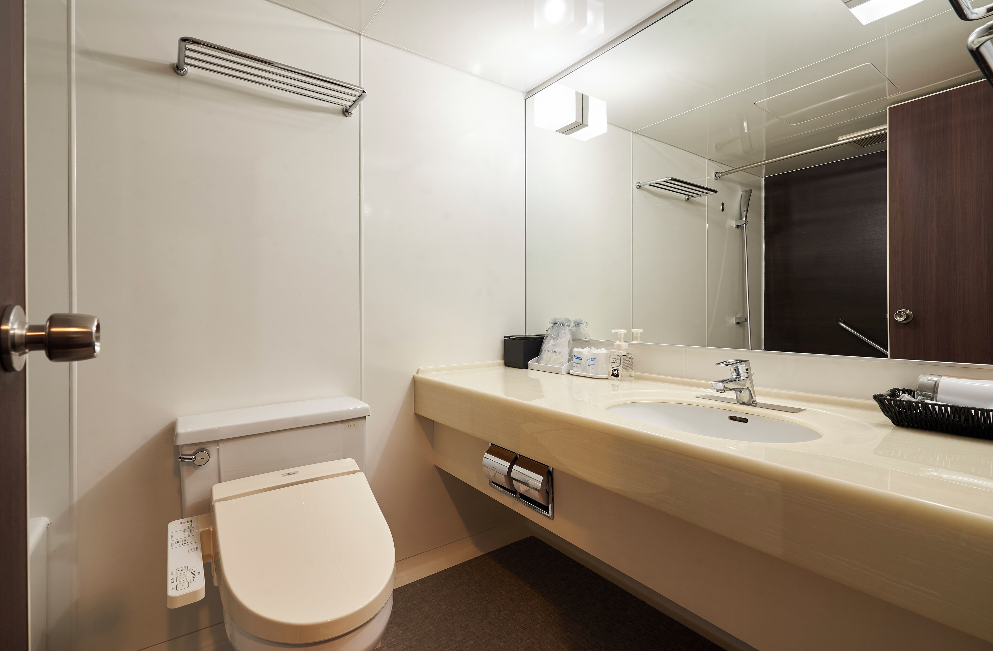 Un baño moderno con inodoro, lavamanos y espejo.