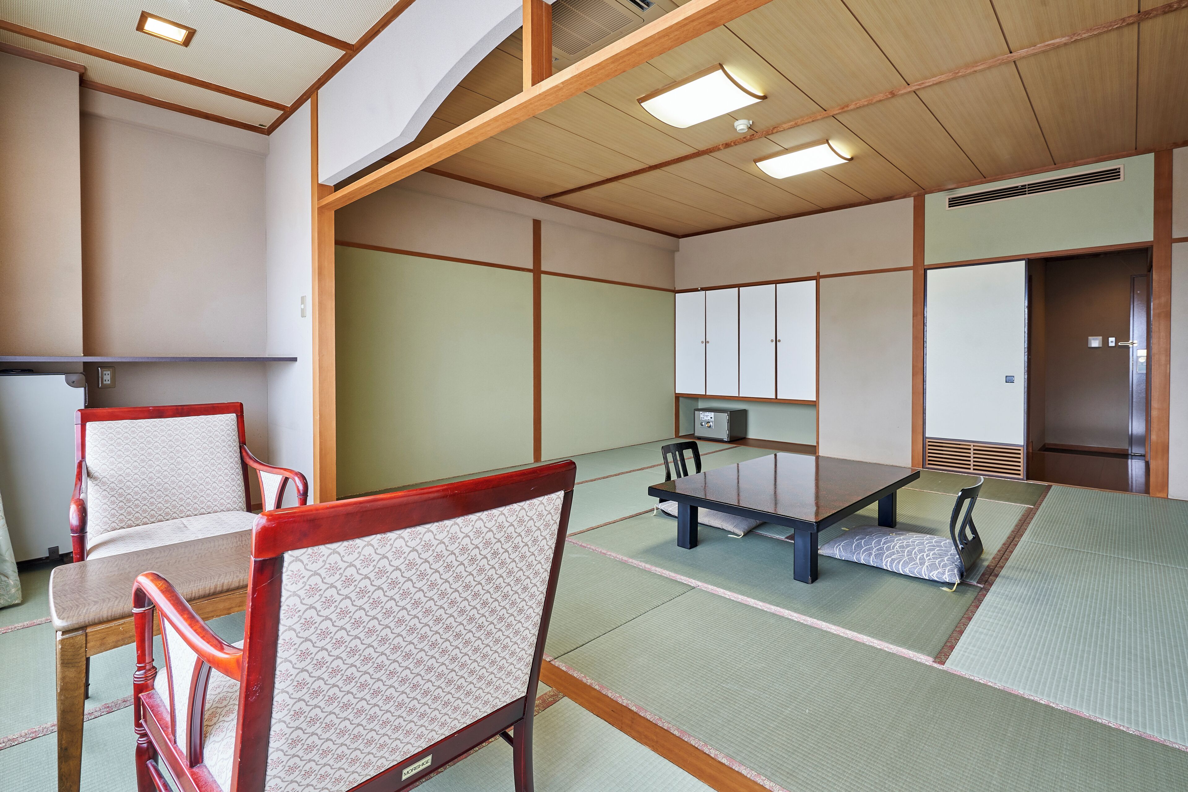 A traditional tatami room with a low table, chairs, and sliding doors.