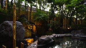 A tranquil indoor garden with a pond, bamboo structures, and a wooden fence.