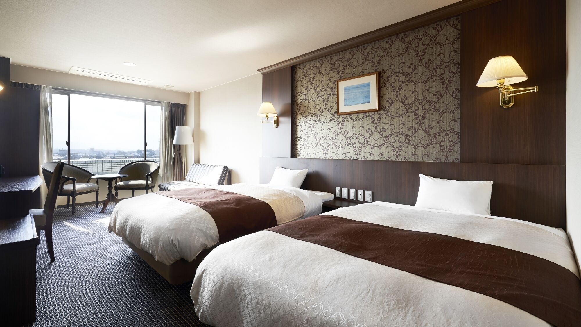 Une chambre d’hôtel avec deux lits, un bureau, une chaise et une vue sur la ville.