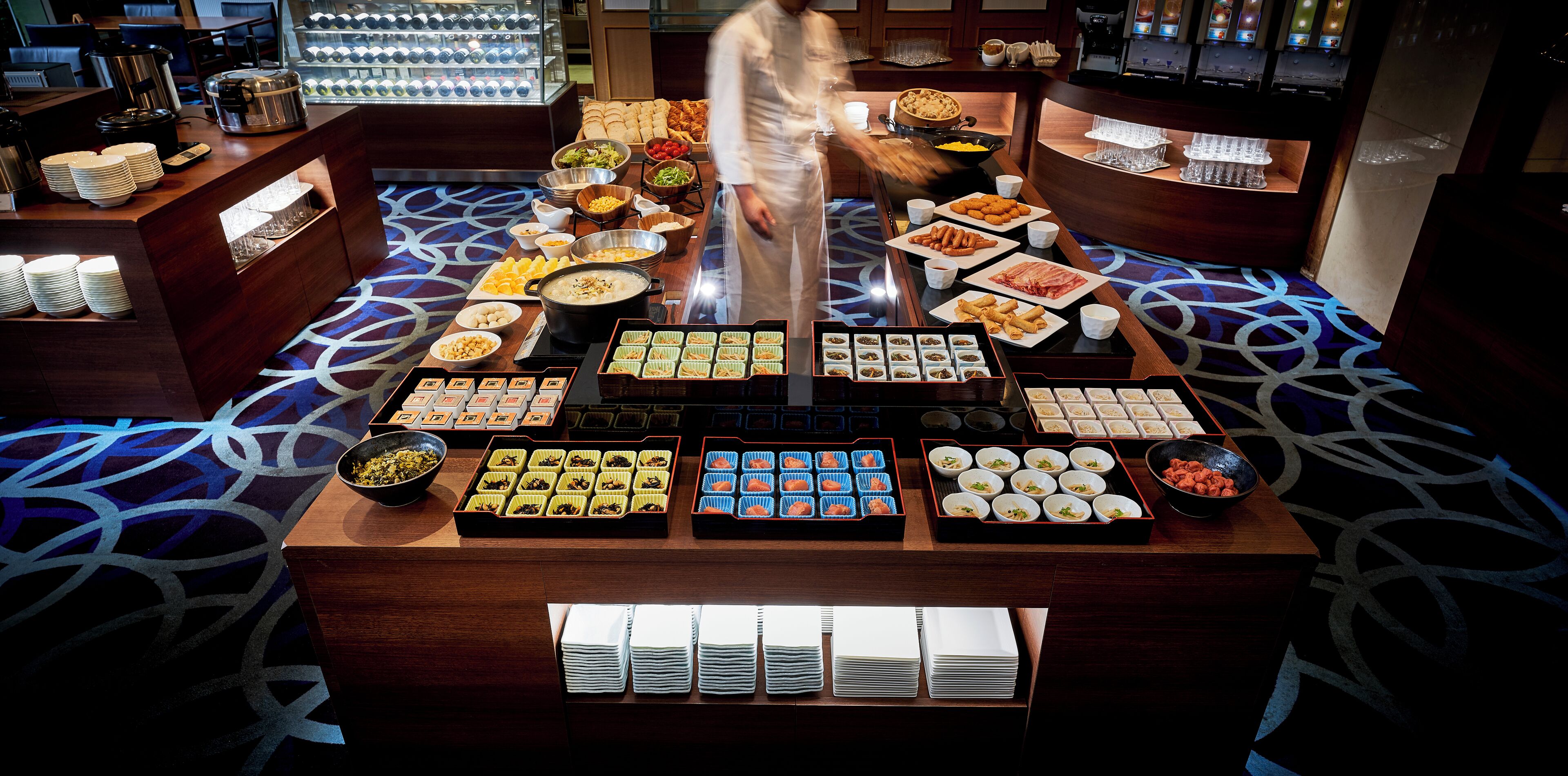 Un buffet proposant une variété de plats et un chef qui prépare les aliments.