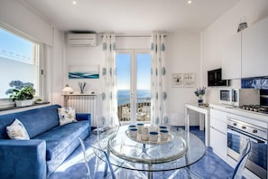 Une cuisine moderne avec une table à manger en verre, un canapé bleu et une vue par les fenêtres.