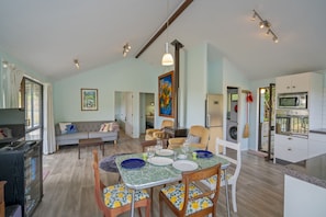A spacious living area with a dining table set for four, a sofa, and a kitchen with modern appliances.