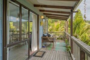 Une terrasse en bois avec un banc et une table, donnant sur un jardin luxuriant.