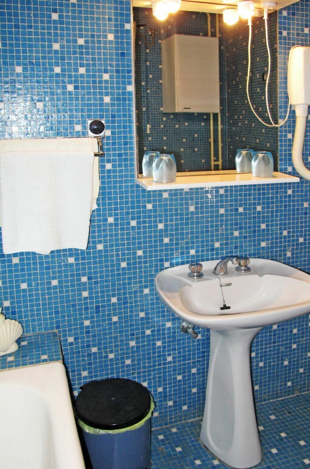 A bathroom with a sink, mirror, and blue mosaic tiles.