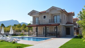 A two-story house with a swimming pool, a covered patio, and a view of mountains. - KONAK SARİ (Ortaca)