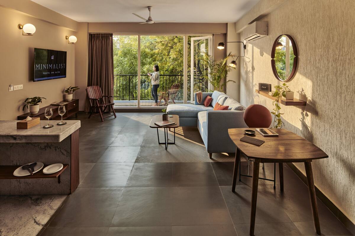 Un salon moderne avec un canapé, une table à manger et un balcon offrant une vue sur les arbres.