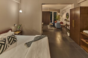 Ein modernes Hotelzimmer mit einem großen Bett, einem Schreibtisch und einer Sitzecke mit einer Couch und Sesseln.