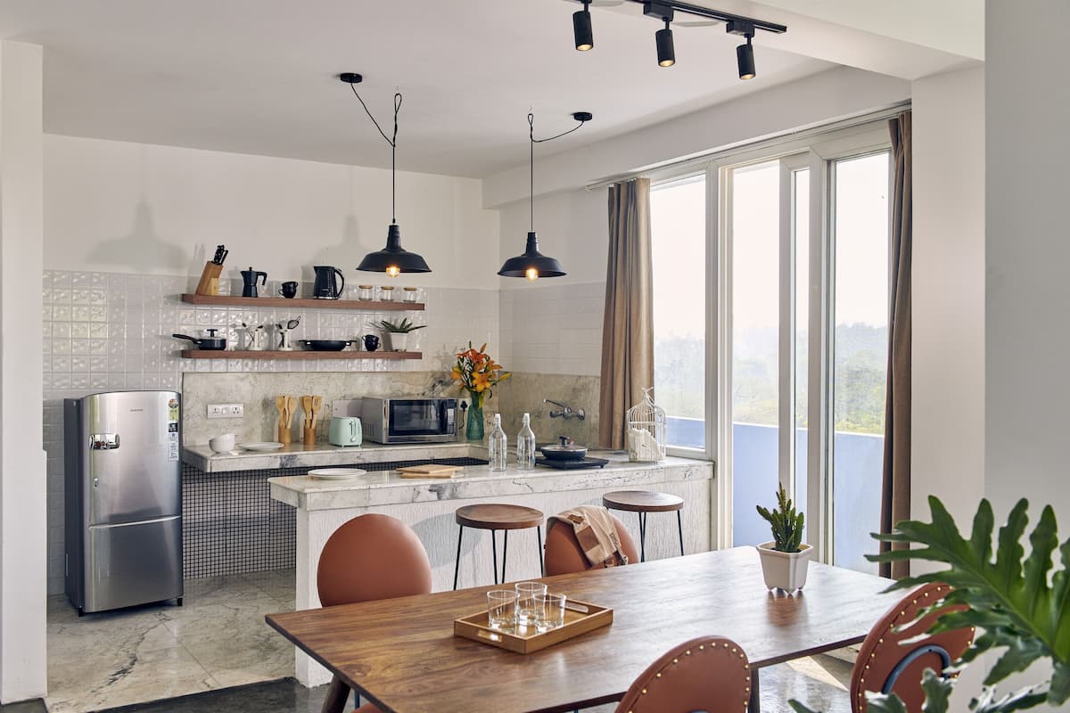Une cuisine moderne équipée d’un réfrigérateur, d’un four à micro-ondes et d’un coin repas avec une table et des chaises en bois.