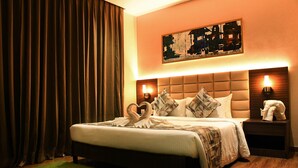 A hotel room with a large bed, a green rug, a headboard with a light, and a painting on the wall. - Lynq Aero (Barasat)