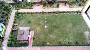 An aerial view of a courtyard with a central lawn, surrounding pathways, and a small pavilion. - Lynq Aero (Barasat)