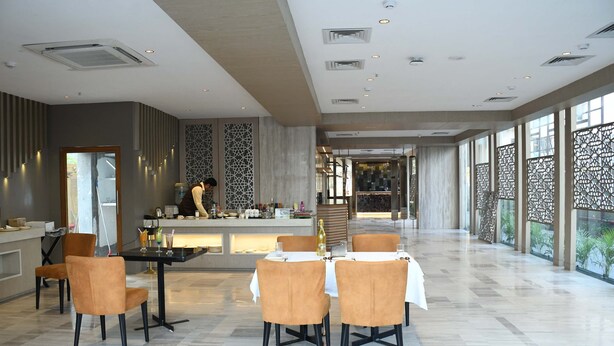 A spacious hotel lobby with a central bar area, seating arrangements, and large windows offering views. - Lynq Aero (Barasat)