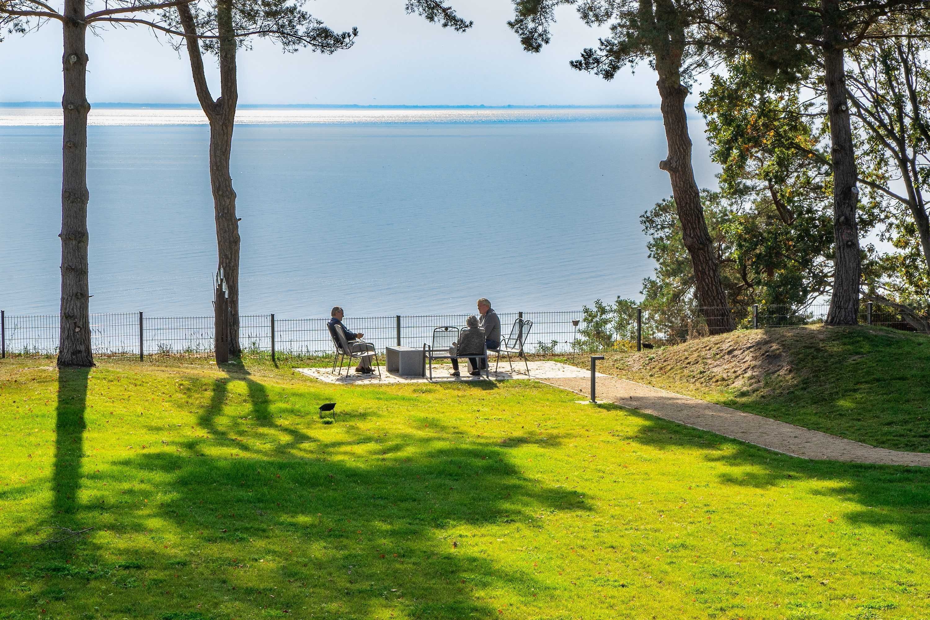 A park with a view of a body of water, benches, and a walking path.