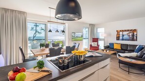 Eine moderne Küche mit Kochinsel, Essbereich mit Aussicht und ein Wohnzimmer mit Sofa und Kunstwerken.