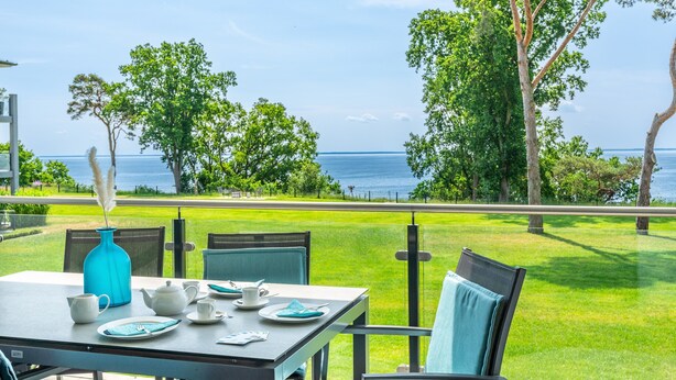 Ein Esstisch mit Meerblick, Gartenstühle und eine blaue Vase.