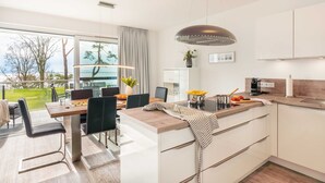 A modern kitchen with a dining area, large windows, and a view of the outdoors. - Apartment Wolkenschiff - Oasis on the lagoon - Wolkenschiff (6-3) (Garz/Usedom)