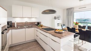 Una cocina moderna con armarios blancos, encimera de madera y un comedor con mesa y sillas.