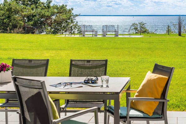 Un espace extérieur aménagé avec une table et des chaises, donnant sur une étendue d’eau.