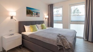Una habitación de hotel moderna con una cama grande, lámparas de noche, una mesita de noche y una ventana con cortinas.