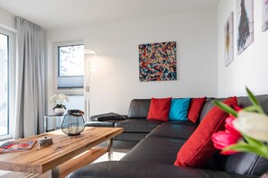 Un salon moderne avec un canapé en cuir noir, une table basse en bois et un lampadaire.