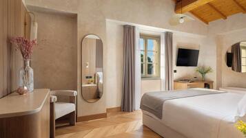Une chambre d’hôtel avec un lit, une table de chevet, un miroir, une télévision et une fenêtre avec des rideaux.