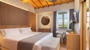 Une chambre avec un grand lit, une table de chevet, un miroir, une fenêtre donnant sur un beau paysage et un téléviseur.