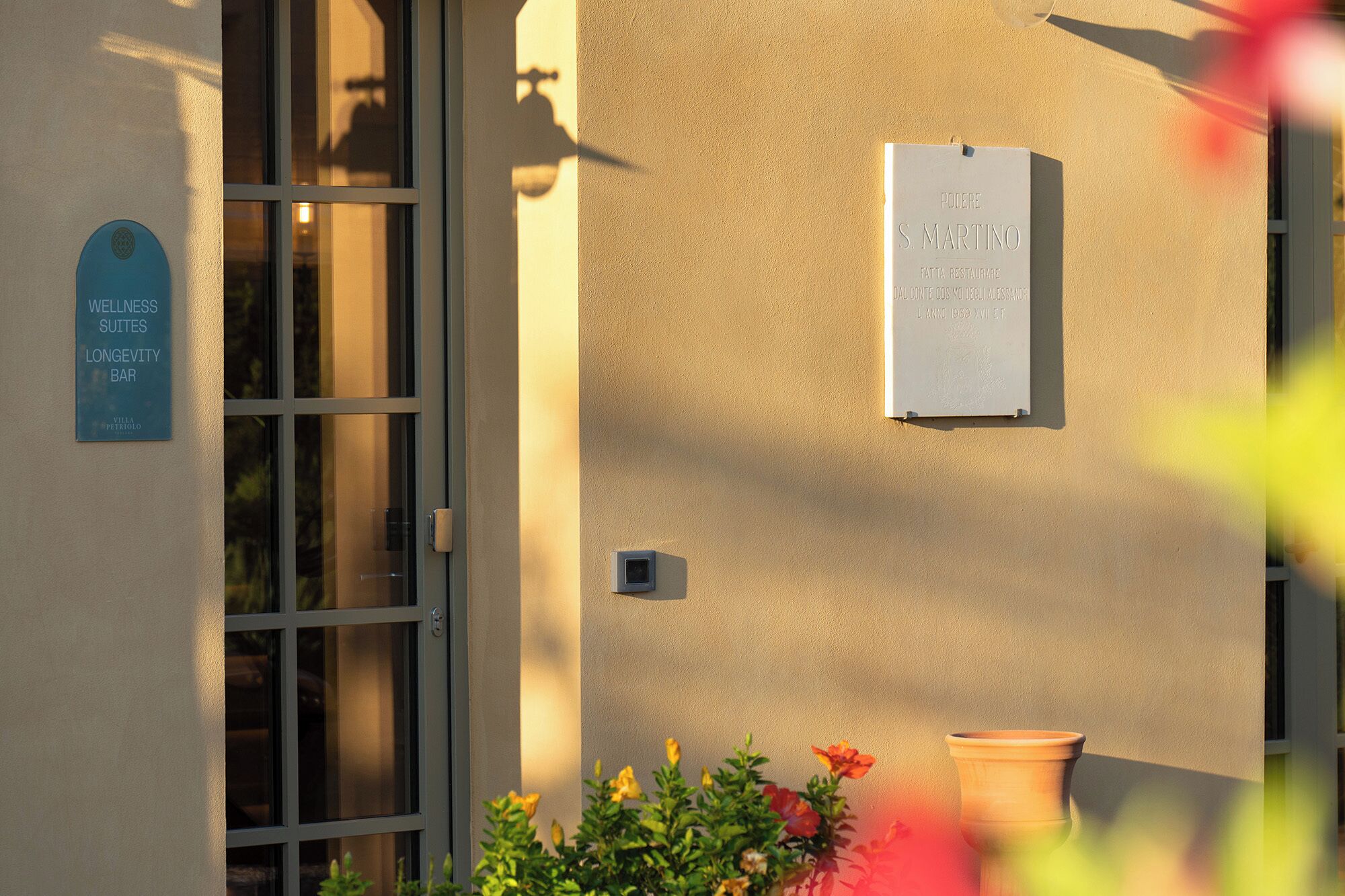 La façade d’un immeuble porte une enseigne indiquant « Wellness Suites Longevity Bar » et une autre enseigne indiquant « PODERE S MARTINO », ce qui laisse supposer qu’il s’agit d’un restaurant.